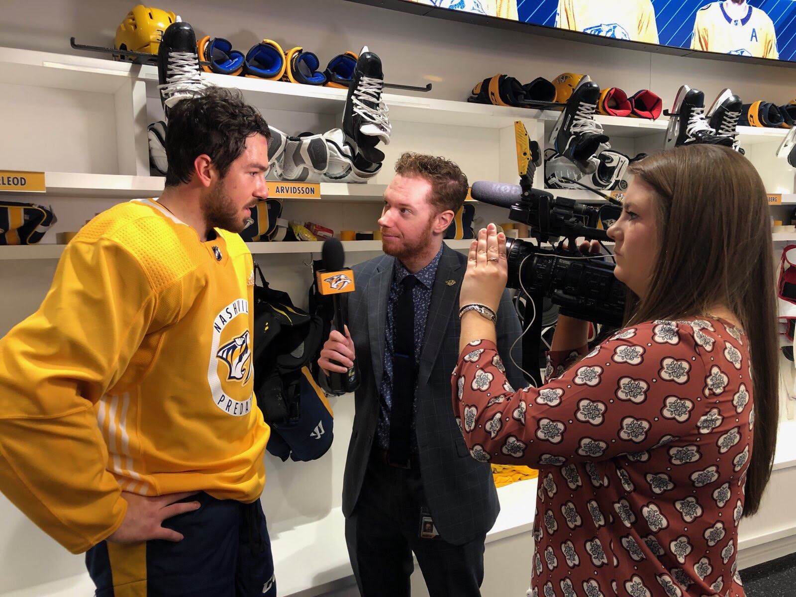 Loyola student Claire Filpi, right, films an interview with Nashville Predators winger Fredrick Grudreau, left, and interviewer Brooks Bratten.